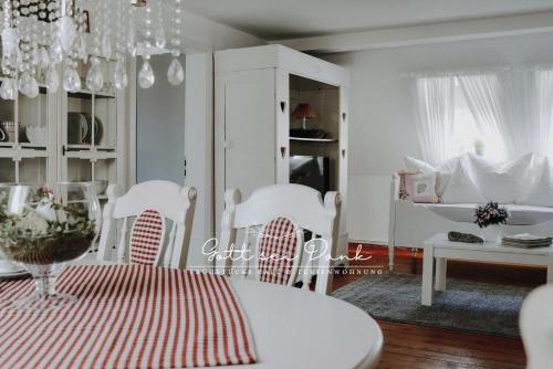a dining room with a table and white chairs at Ferienwohnung "Gott sei Dank" in Herzberg am Harz