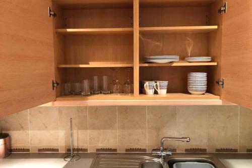 a kitchen with wooden cabinets with plates and a sink at 2 bedroom appartment loch lomond in Balloch