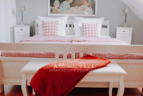 a bedroom with two beds and a red blanket on a bench at Ferienwohnung "Gott sei Dank" in Herzberg am Harz