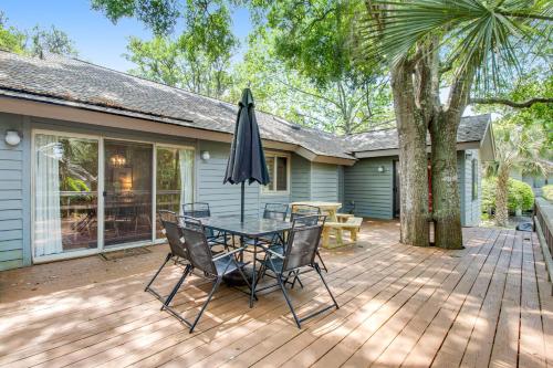 eine Terrasse mit Tisch und Sonnenschirm in der Unterkunft 460 Oceanwoods Cottage in Kiawah Island