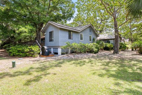 ein blaues Haus mit Bäumen und einem Garten in der Unterkunft 460 Oceanwoods Cottage in Kiawah Island