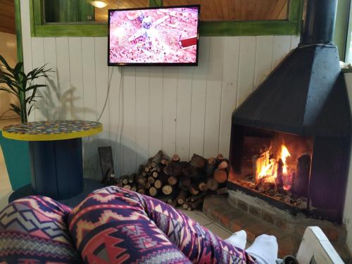 a living room with a fireplace and a tv at Pousada Quintal Verde Floripa in Florianópolis