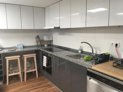 a kitchen with white cabinets and a sink and a counter at Barão Guesthouse in Vouzela