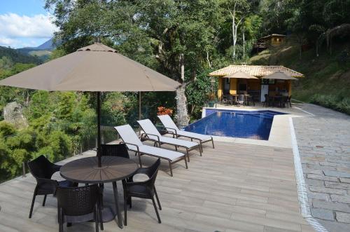 a patio with chairs and an umbrella and a pool at Vaca do Brejo, piscina aquecida, sauna, A/C quente in Petrópolis