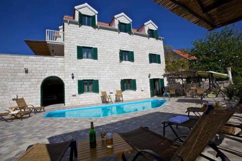 ein Gebäude mit einem Swimmingpool davor in der Unterkunft Villa Monica in Ložišće