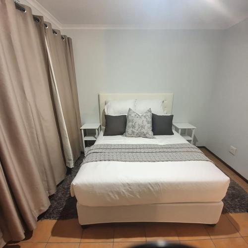 um quarto com uma grande cama branca com cortinas em Cosy, stylish, 2 bed apartment, free wifi, Netflix, dstv now em Midrand