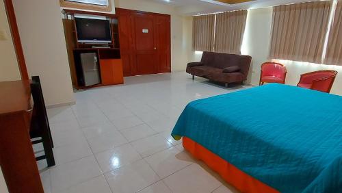 a hotel room with a bed and chairs and a television at Hotel El Marques in Mérida