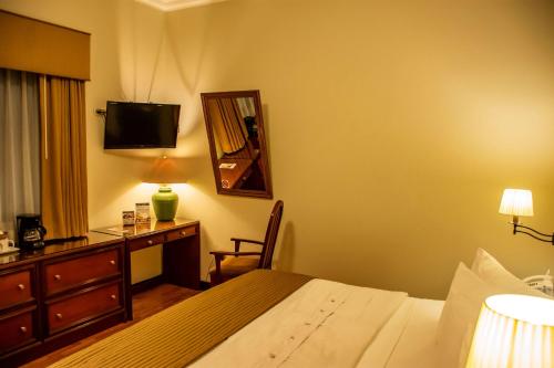 a hotel room with a bed and a desk and a television at Best Western Plus Hotel Stofella in Guatemala