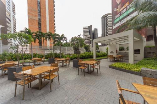 a patio with wooden tables and chairs in a city at Apartamento 2 quartos May Way Meireles uma quadra da Beira-mar in Fortaleza