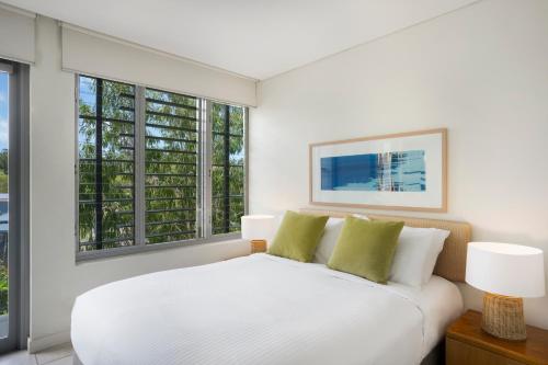 a bedroom with a white bed and two windows at Peppers Blue on Blue in Nelly Bay
