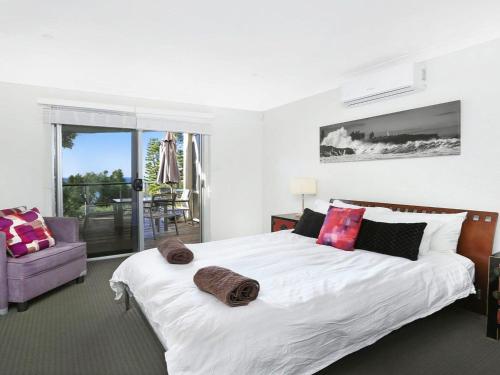 a bedroom with a large white bed and a chair at Santa Barbara on Bombo Beach in Kiama