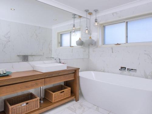 a white bathroom with a tub and a sink at Kendalls Beach House in Kiama