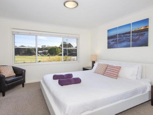 Un dormitorio con una gran cama blanca y una silla. en Kendalls One, en Kiama
