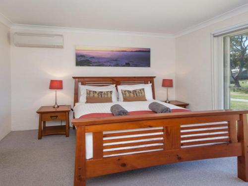 Un dormitorio con una gran cama de madera con dos lámparas. en Kendalls Two, en Kiama