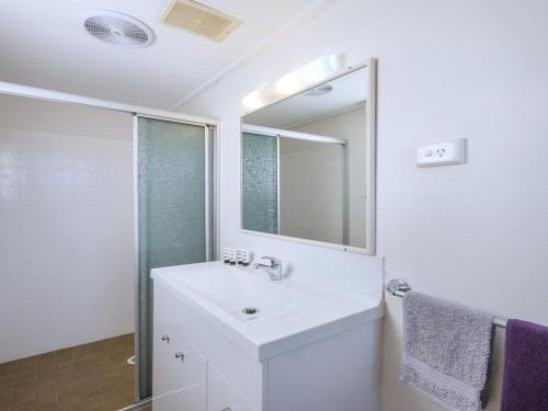 Un baño blanco con lavabo y espejo. en Kendalls Two, en Kiama