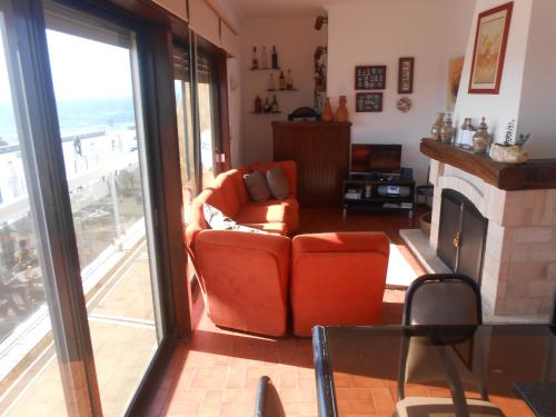 a living room with an orange chair and a fireplace at Casa na Praia do Mindelo in Mindelo