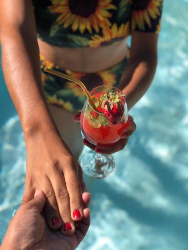 a woman in a bikini holding a drink in front of a pool at Zuri Pousada Maragogi in Maragogi