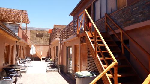 a wooden staircase next to a building with tables and chairs at Vicuña Lodge in San Pedro de Atacama