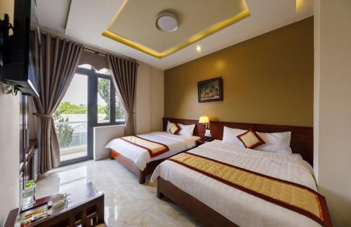 Cette chambre comprend deux lits et une télévision. dans l'établissement Bonjour Da Lat Hotel, à Đà Lạt