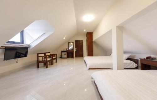 a attic bedroom with two beds and a tv at Bonjour Da Lat Hotel in Da Lat