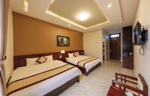a hotel room with two beds and a television at Bonjour Da Lat Hotel in Da Lat