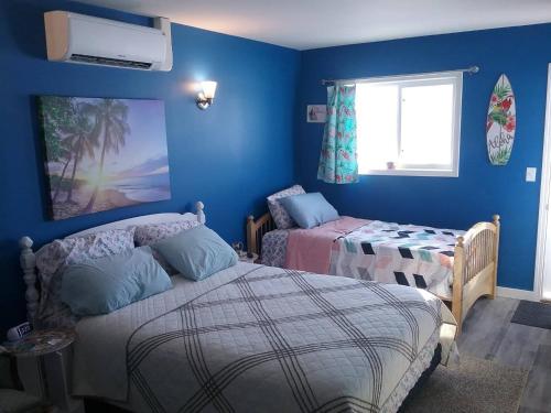 a blue room with two beds and a window at Beach Mirage Suites in Brook Park