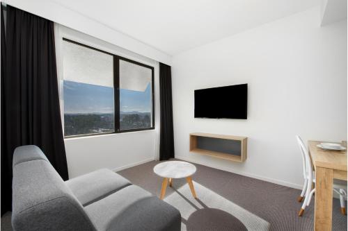 a living room with a couch and a table and a window at Mantra MacArthur Hotel in Canberra