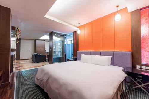 a bedroom with a large bed with an orange wall at Shianghu Boutique Hotel in Chiayi City