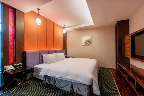 a hotel room with a bed and a flat screen tv at Shianghu Boutique Hotel in Chiayi City