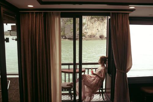 a woman sitting on a balcony looking out of a window at Sena Cruises - Wonder On Lan Ha Bay in Ha Long