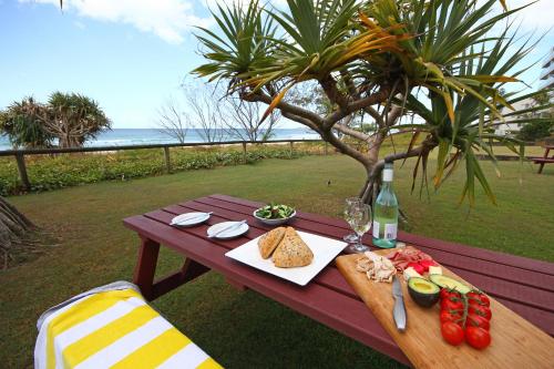 a picnic table with food and a bottle of wine at San Simeon Beachfront Apartments Tugun in Gold Coast