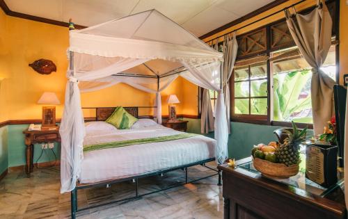 a bedroom with a canopy bed and a basket of fruit at Jogja Village in Yogyakarta