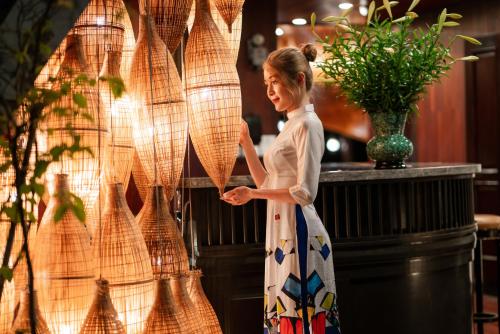 a woman in a dress standing next to a wall at Sena Cruises - Wonder On Lan Ha Bay in Ha Long