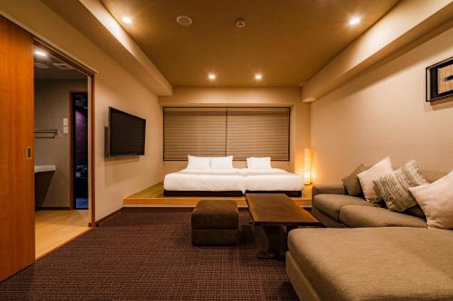 a hotel room with a bed and a couch at Randor Residential Hotel Kyoto Suites in Kyoto
