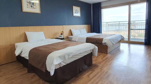 Habitación de hotel con 2 camas y ventana grande. en Blue Hawaii Resort en Jeju