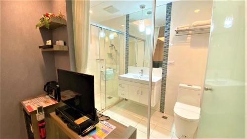 a bathroom with a shower and a toilet and a television at Taitung Z. Hotel in Taitung City