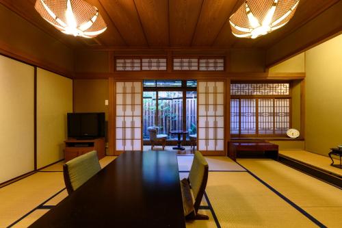 a dining room with a table and chairs and a tv at Kappo Ryokan Yumesaki in Beppu