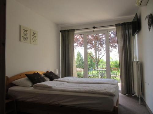 um quarto com uma cama e uma grande janela em Mediterrán Vendégház em Velence