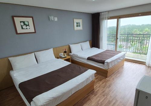 um quarto de hotel com duas camas e uma varanda em Blue Hawaii Hotel em Jeju