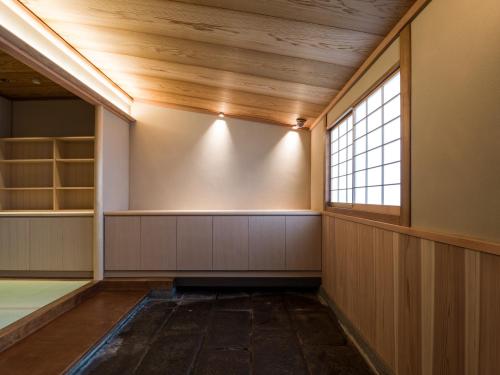 an empty room with a window and a large wall at Kappo Ryokan Yumesaki in Beppu