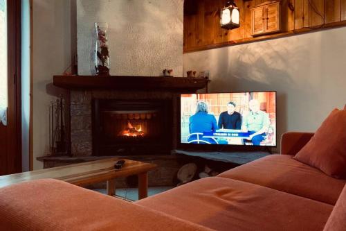 a living room with a tv and a fireplace at Baita Coccola nel Bosco Sport Natura Relax in Scopello