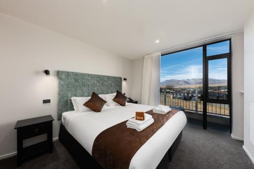 ein Schlafzimmer mit einem großen Bett und einem großen Fenster in der Unterkunft Galaxy Boutique Hotel in Lake Tekapo