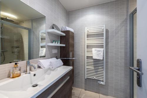 une salle de bain avec un lavabo et un miroir dans l'établissement Le Lympia, à Nice
