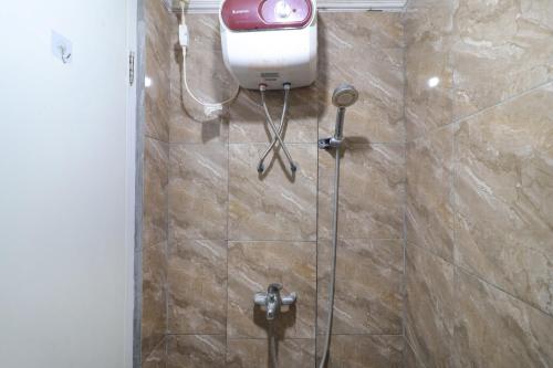 a shower stall with a soap dispenser on the wall at The Suite Metro Apartment by King Official in Bandung