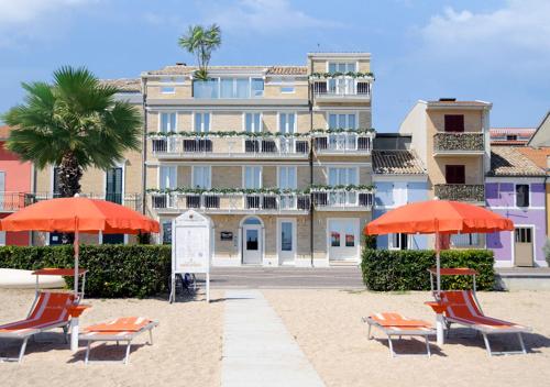 ポルト・レカナーティにあるOpera Arte Suite Apartmentsの建物の前のビーチ(椅子、パラソル付)