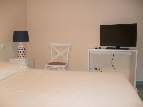 a bedroom with a bed and a desk with a television at VILLA FLORA ARGENTARIO in Porto Santo Stefano