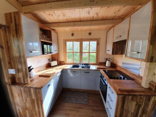 a kitchen with white cabinets and wooden ceilings at East Pool Cabin in Lincoln