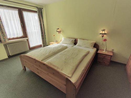 a large bed in a room with two tables and two windows at Pension Berg&Bleibe Wertach in Wertach