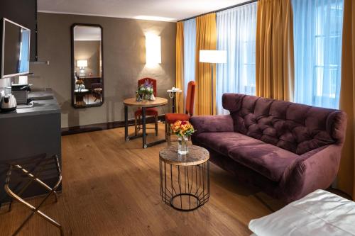 ザルツブルクにあるアルスタッド ホテル スタッドクルーグの紫色のソファとテーブル付きのリビングルーム