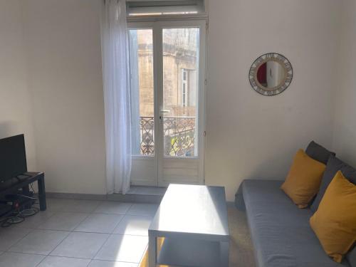 un salon avec un canapé, une table et une fenêtre dans l'établissement Appartement confort centre-ville St Roch, à Montpellier